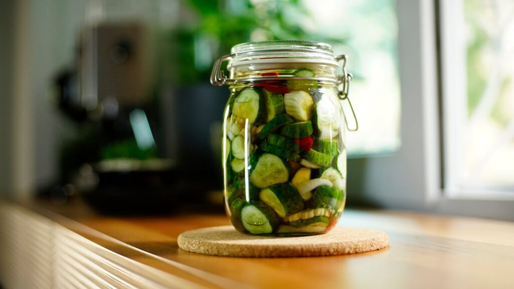 Close-up of a jar filled with fresh homemade cucumber pickles on a kitchen counter.