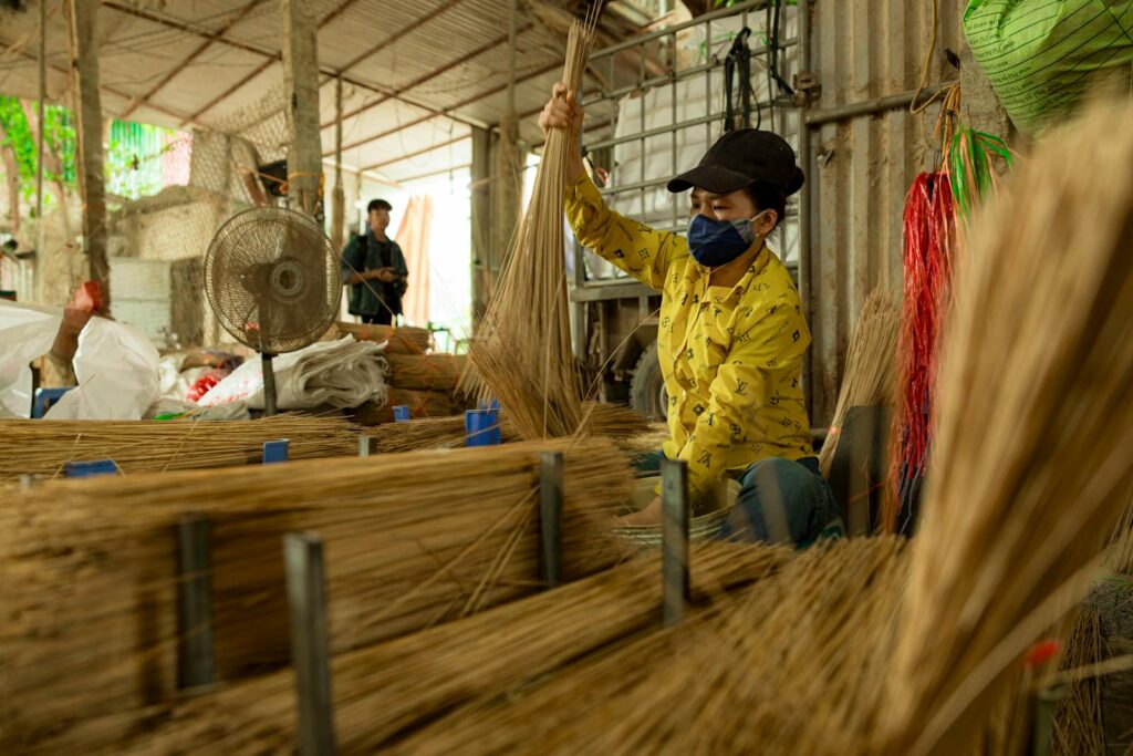 A skilled artisan crafting brooms in a rustic workshop, highlighting traditional craftsmanship.