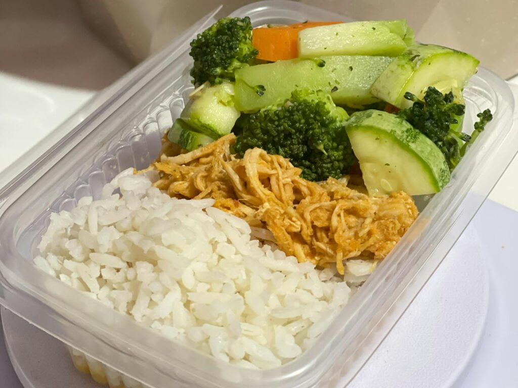 A nutritious meal prep box with rice, shredded chicken, and mixed vegetables.