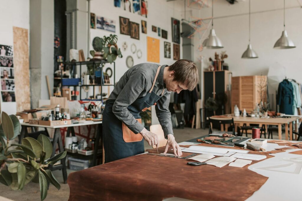 Skilled craftsman cutting leather in a well-organized workshop.