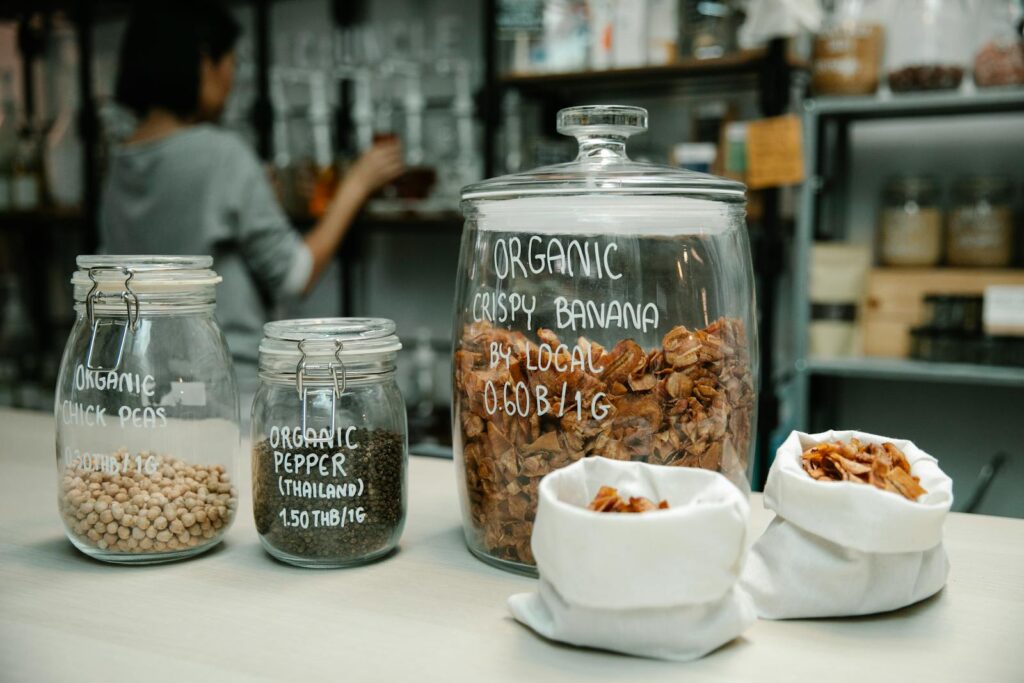 Glass jars with organic chickpeas, pepper, and crispy banana on kitchen counter.