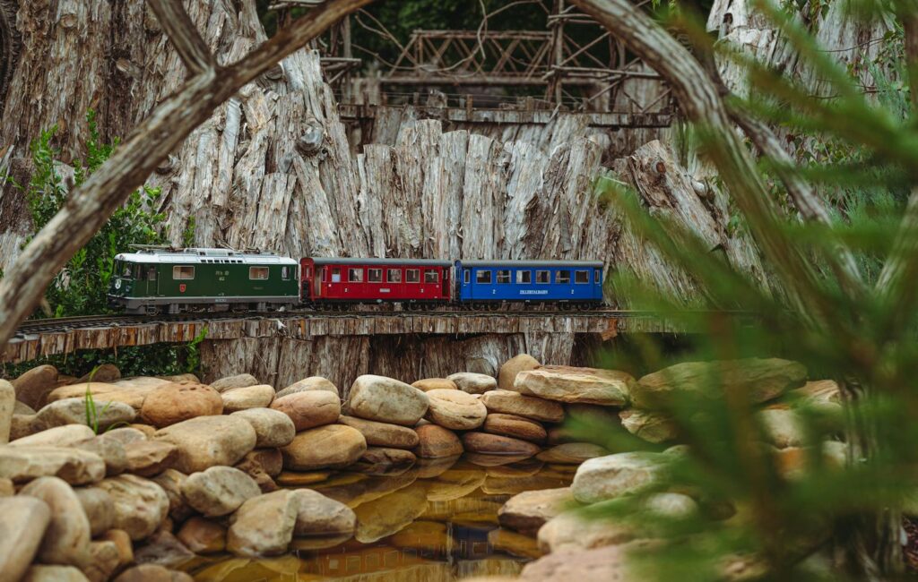 Serene garden scene featuring a colorful miniature train on a track surrounded by rocks and greenery.