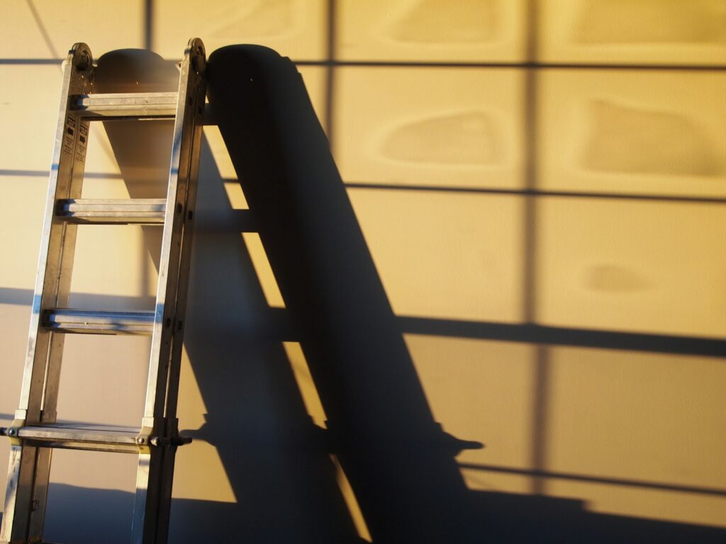 Black metal ladder leaning on white wall