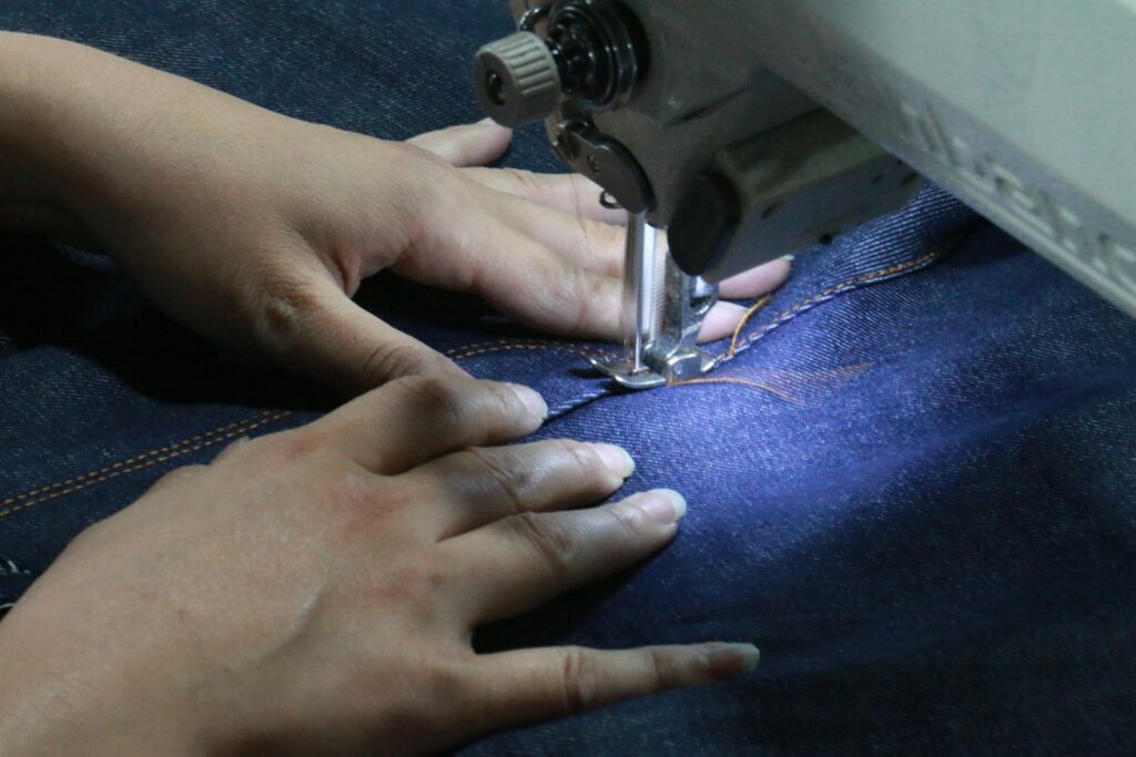 A woman using a sewing machine to sew jeans