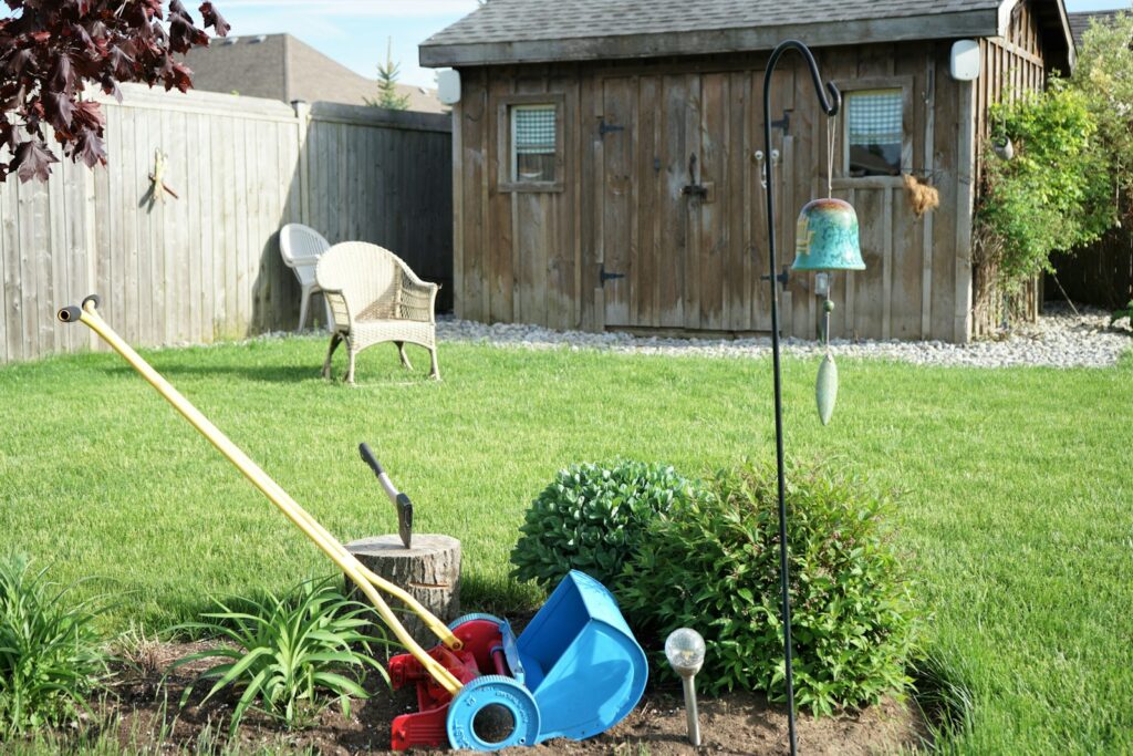A yard with a lawn mower, garden tools and a birdhouse