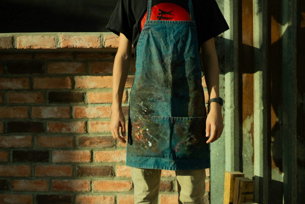 Man in black and red t-shirt and gray pants standing beside brown brick wall