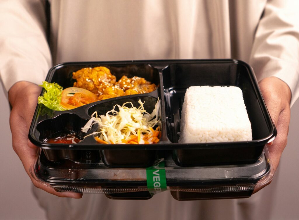 A person holds a bento box meal.
