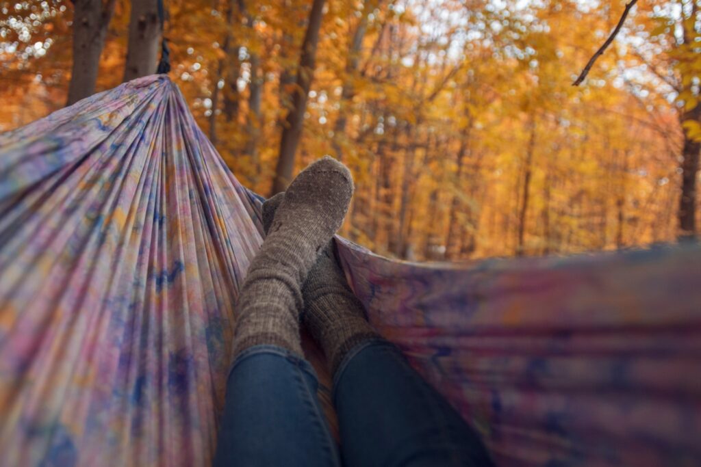 Person lying wearing gray socks lying in multicolored hammock.