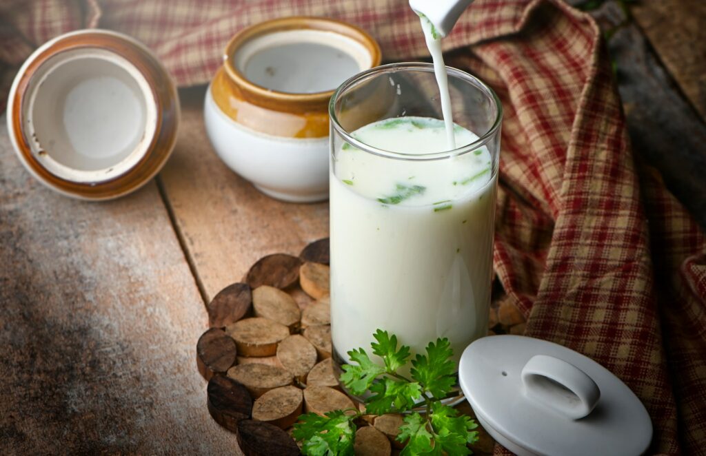 Milk in clear drinking glass with green leaves and white cream.