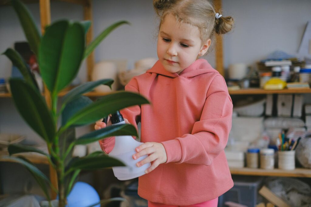 Child in pink sweater watering a plant, promoting eco-friendly habits.