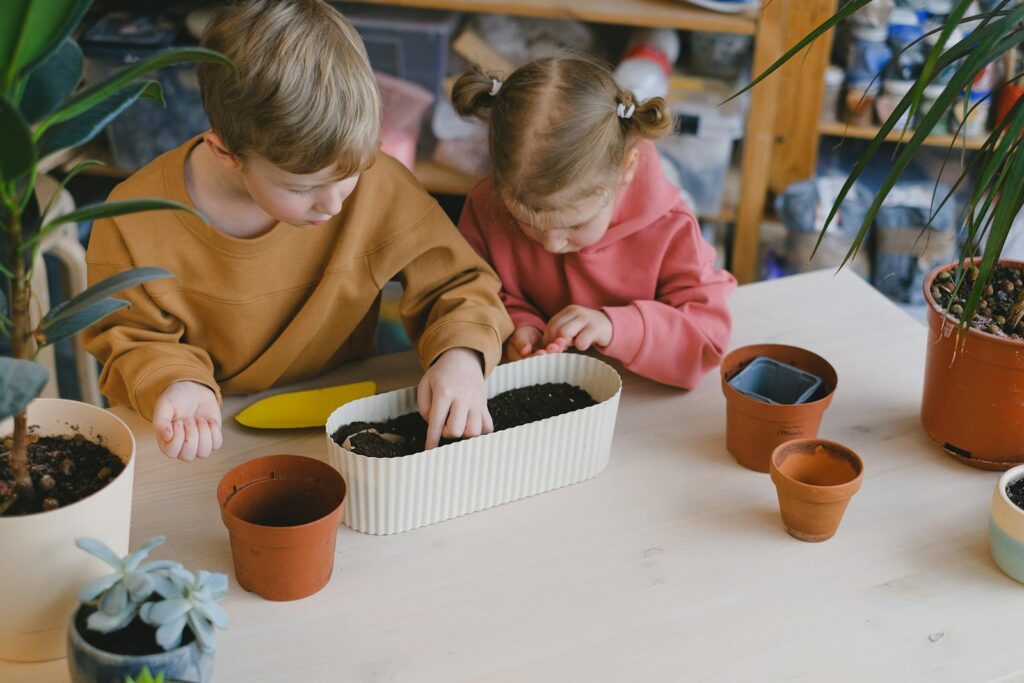 Young children engaging in gardening activities indoors, planting seeds together.