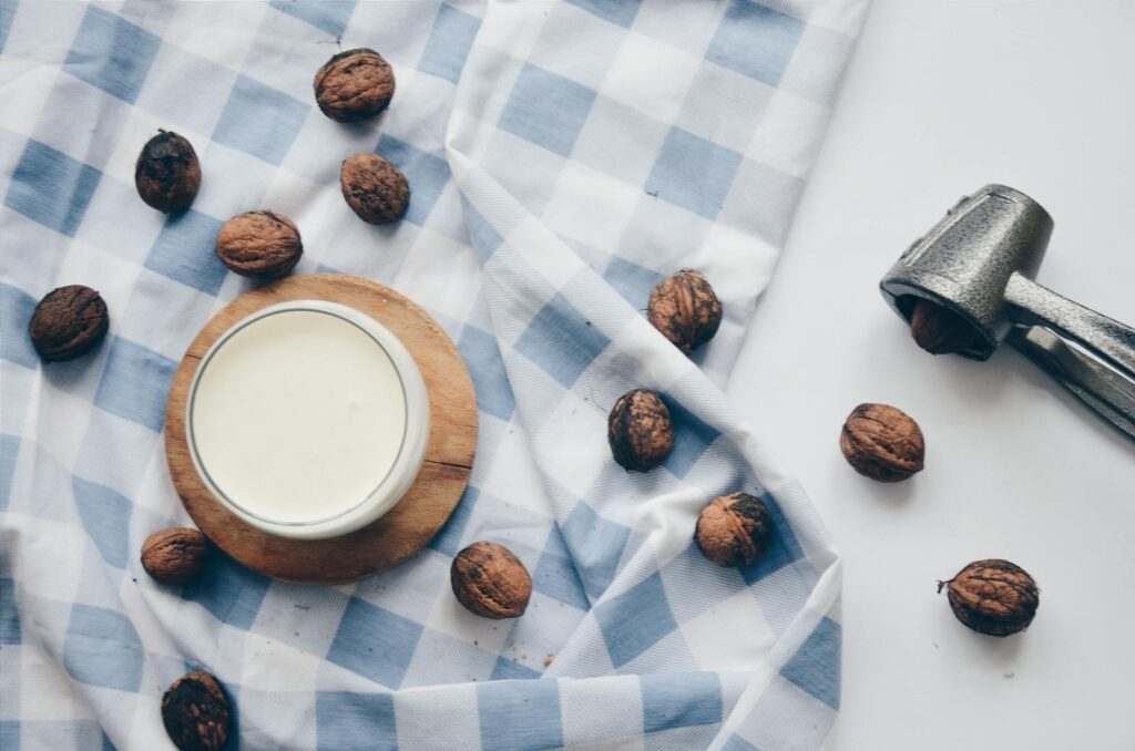 A cozy still life featuring a cup of milk with walnuts and a nutcracker on blue checkered cloth.