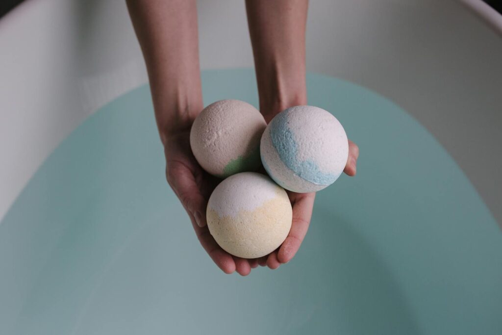 A soothing image of three bath bombs held over a tranquil bath, ideal for relaxation themes.