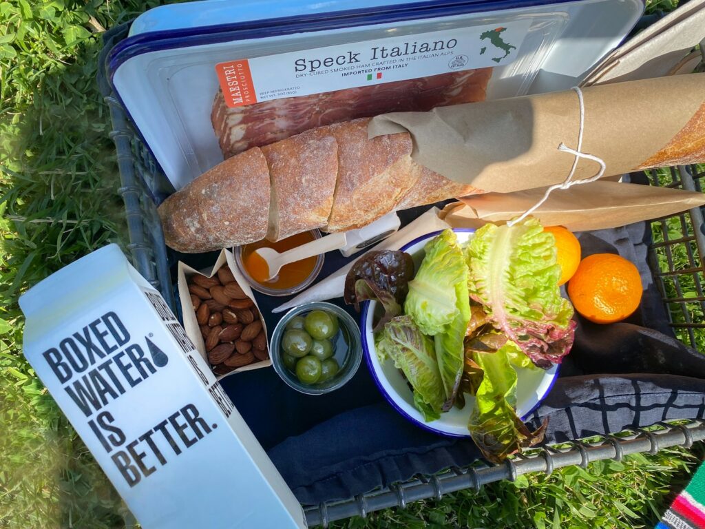 A variety of food is laid out on a picnic blanket.