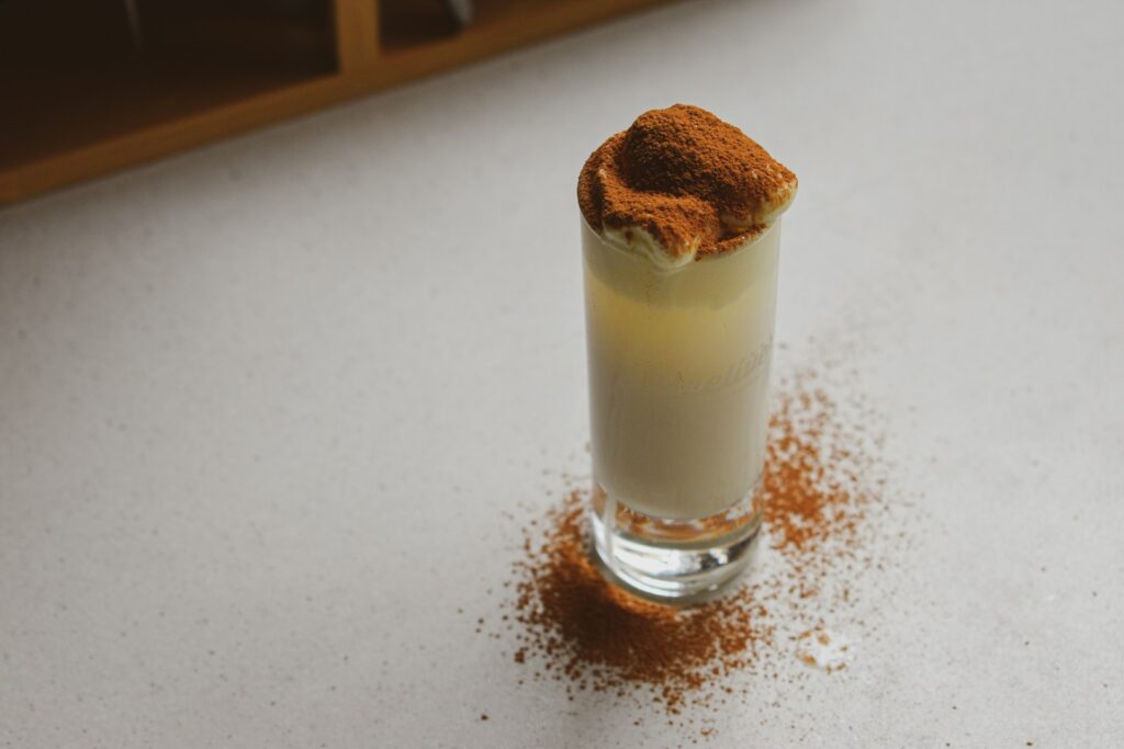 A shot of a milk with cinnamon on the rim.