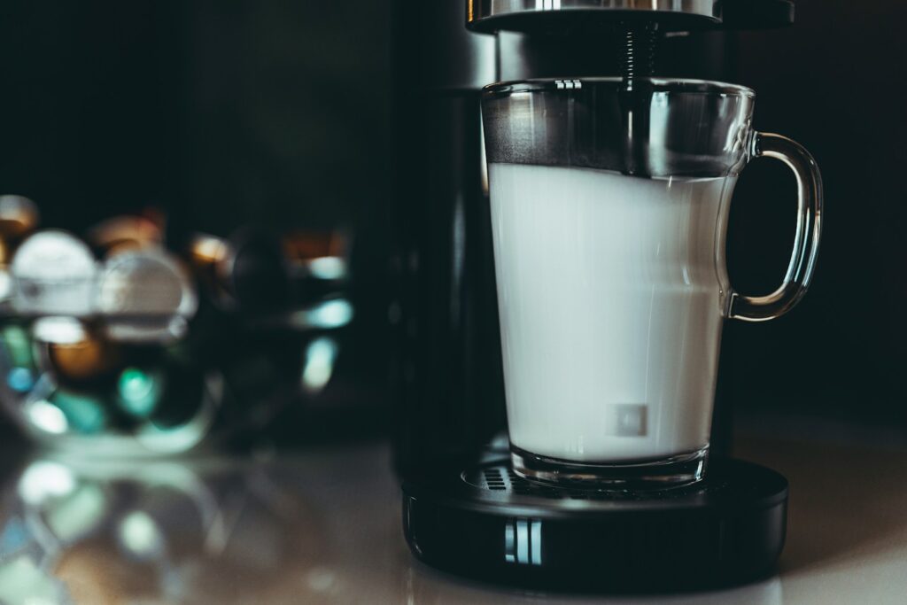 A glass of milk sitting on top of a blender.