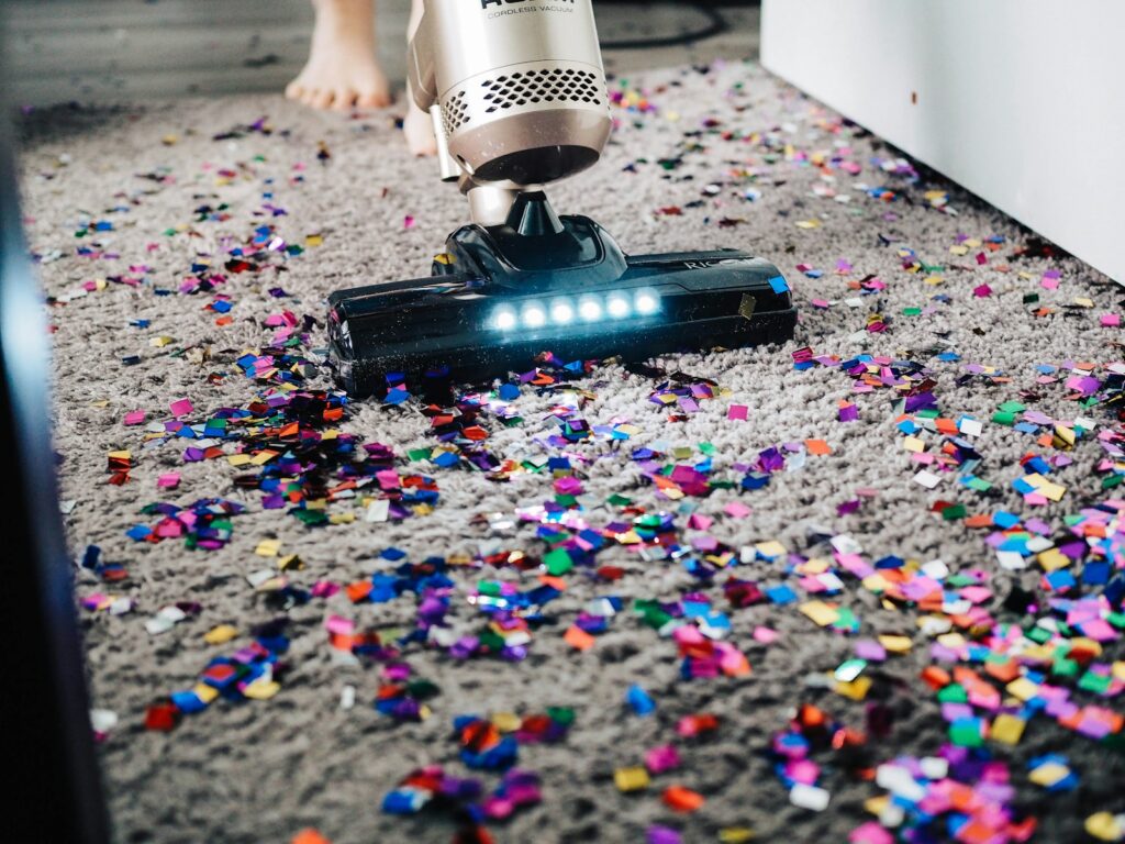 A person using a vacuum to clean a carpet.