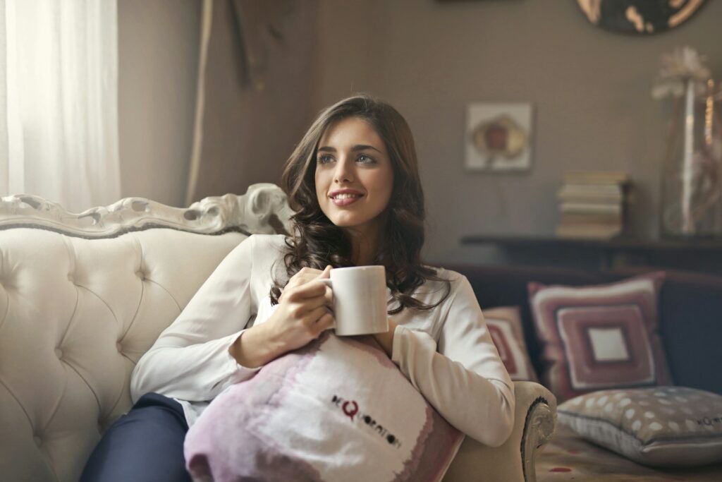 Woman holding mug sitting on sofa.