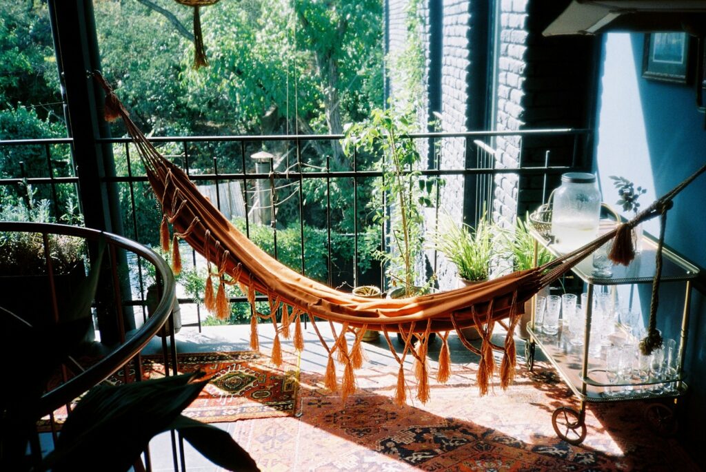 A hammock hanging on a balcony next to a potted plant.