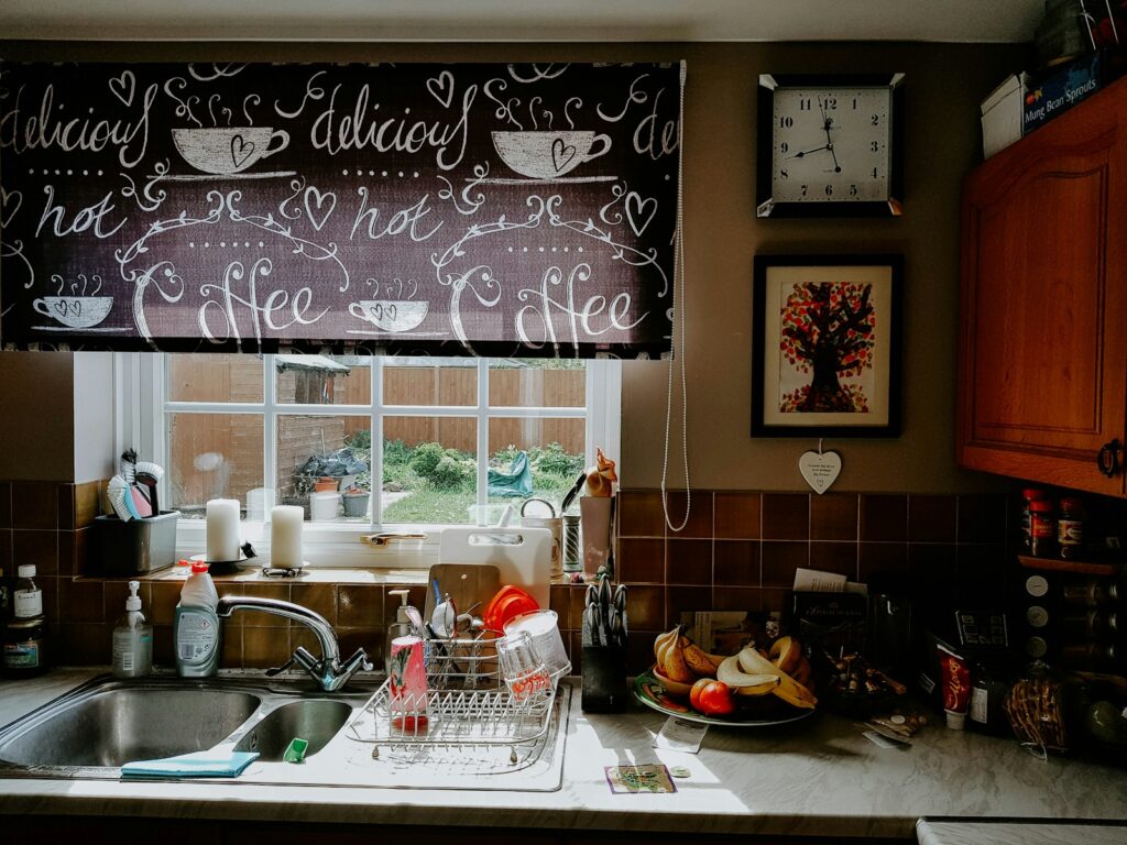 A kitchen sink under a window with a chalkboard above it.