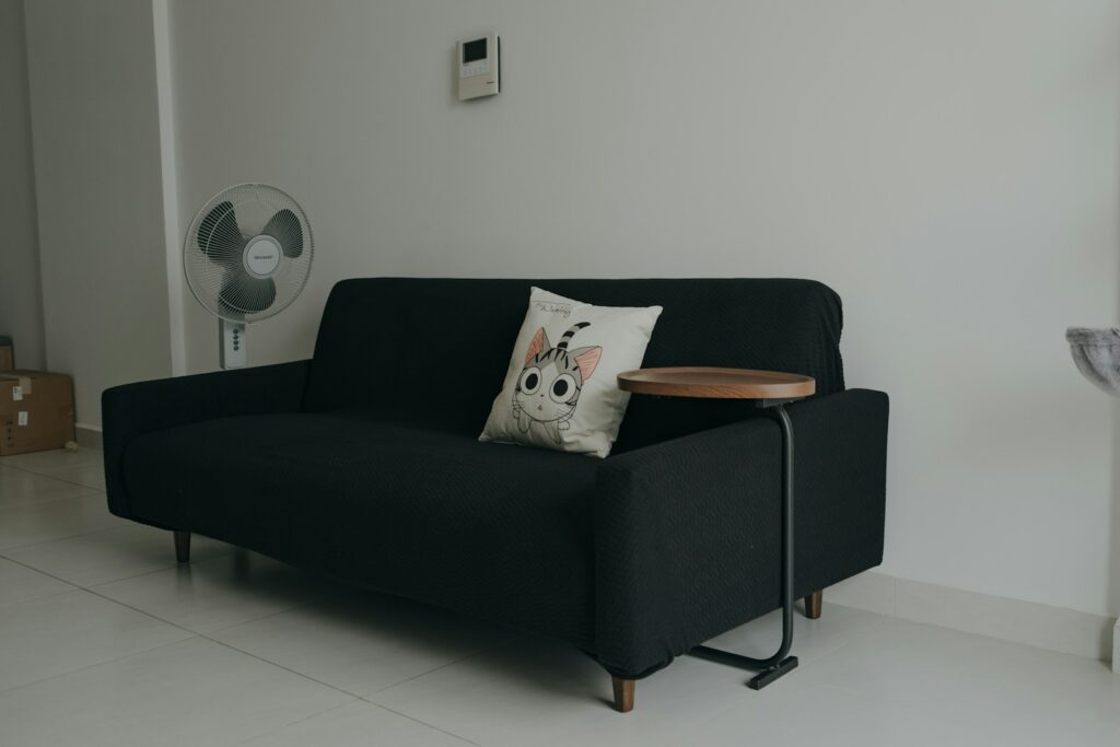 A black couch with a wooden table on top of it.
