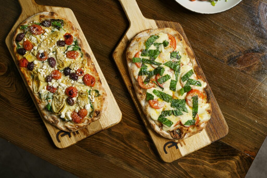 A couple of pizzas sitting on top of a wooden cutting board