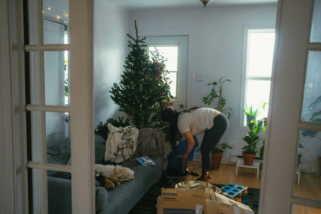 A woman bending over a couch in a living room.