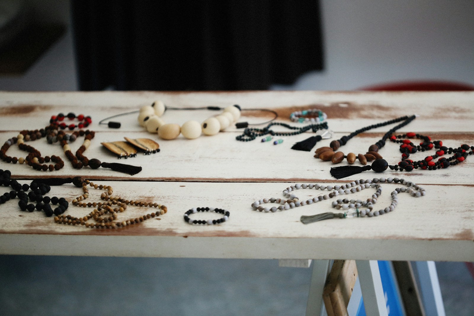 A wooden table topped with lots of necklaces