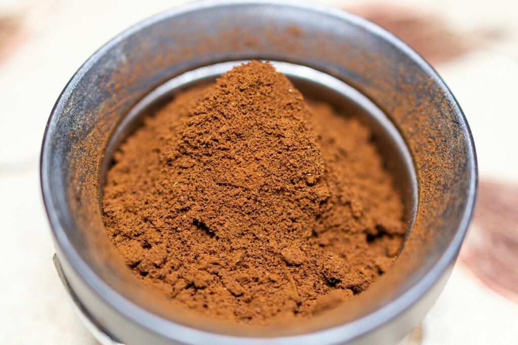A metal bowl filled with cinnamon powder on top of a table.