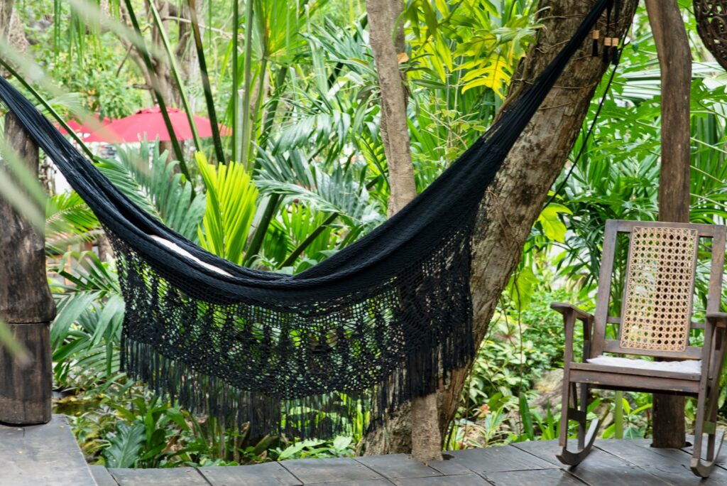 Black hammock hanged on brown wooden fence.