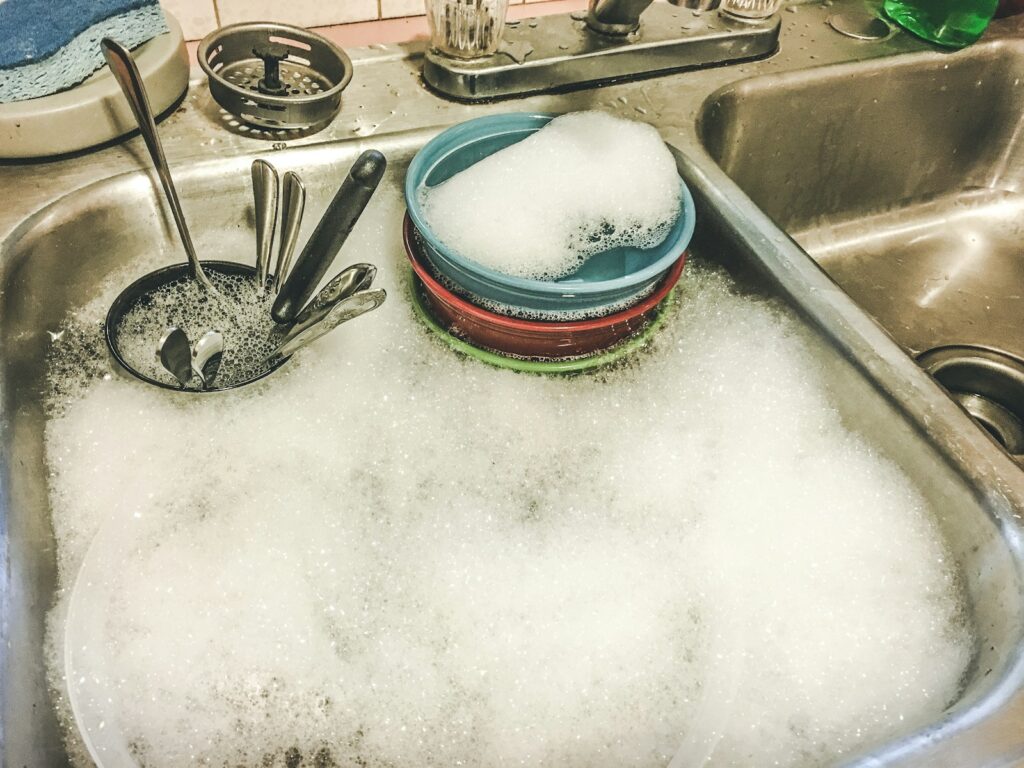 Stainless steel spoons on white ceramic sink.