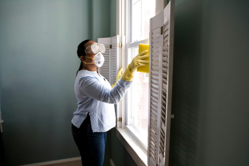 Woman in white long sleeve shirt and blue denim jeans standing beside white wooden framed glass.
