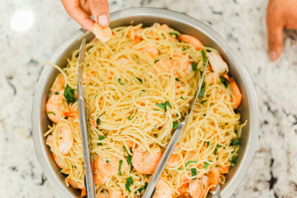 Person holding stainless steel bowl with noodles
