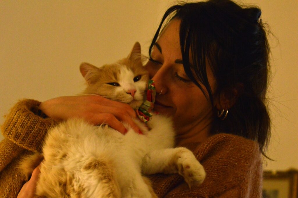 Woman in black tank top holding white cat