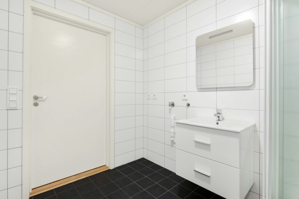 A bathroom with a sink, mirror, and shower stall