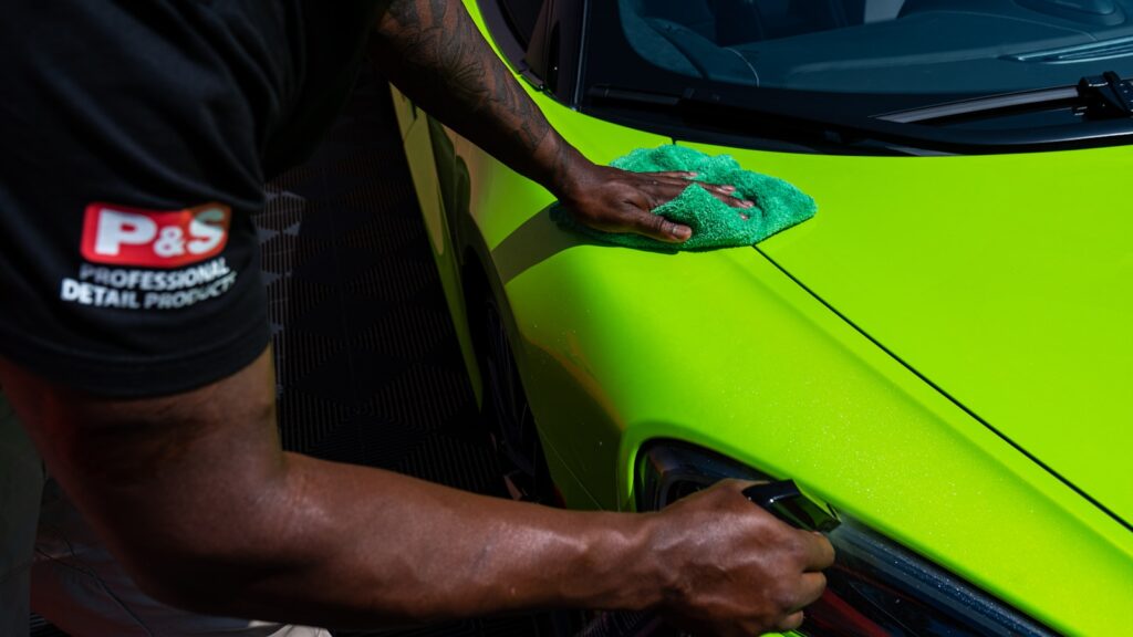 A man polishing the side of a green sports car