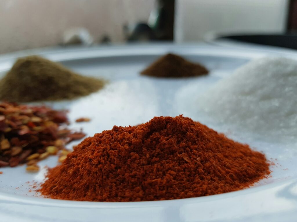A white plate topped with lots of different types of spices like Turmeric.